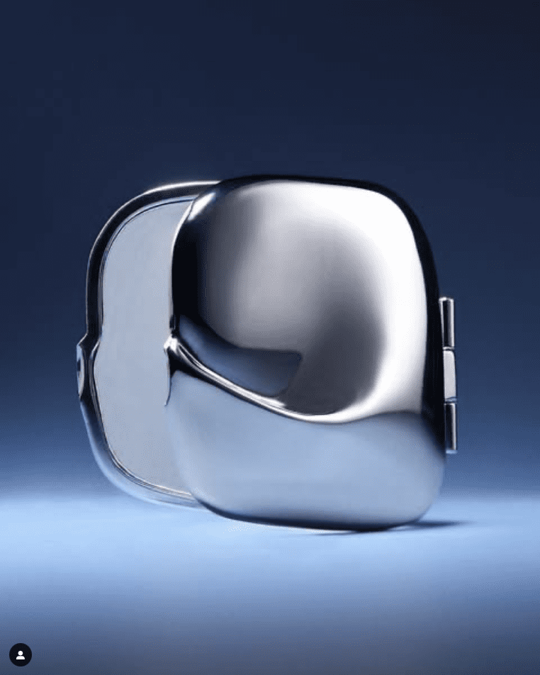 A sculptural silver handbag against a dark blue background.